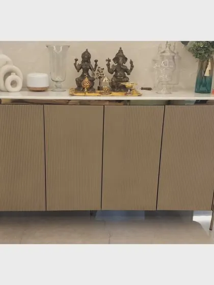 A four-door buffet console with fluted detailing and a marble top, set on slender metal legs. This piece was designed to provide ample storage while maintaining a light and elegant presence in a dining room.