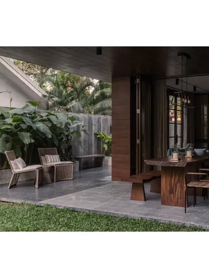 The transition from the lawn to the covered outdoor dining area. We used the same Kota stone flooring to blur the lines between inside and out, a key feature of this modern Bangalore home.