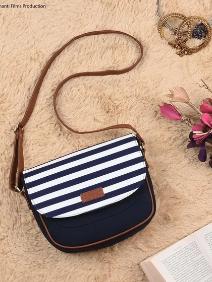 A creative flat-lay of a striped sling bag, styled with props like a book and flowers. This type of lifestyle image is perfect for website banners and Instagram feeds.