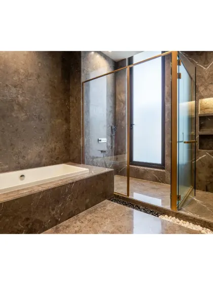 A view of the bathtub and shower area, both clad in the same rich, dark marble. The gold-tinted glass of the shower enclosure adds a touch of warmth and opulence.
