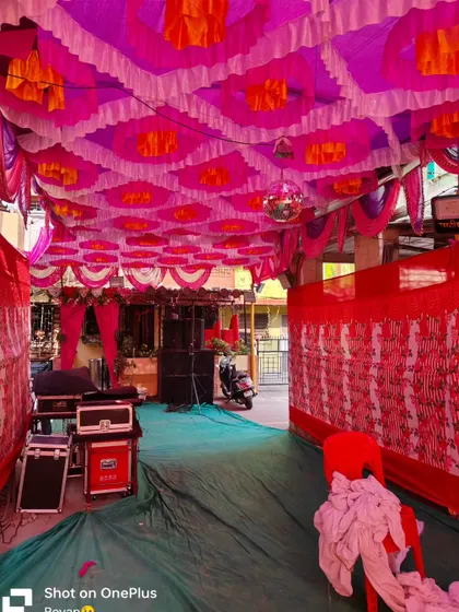 A colorful pandal setup for a Haldi event. The pink and orange ceiling drapes and the DJ sound system show that this space is ready for a party.