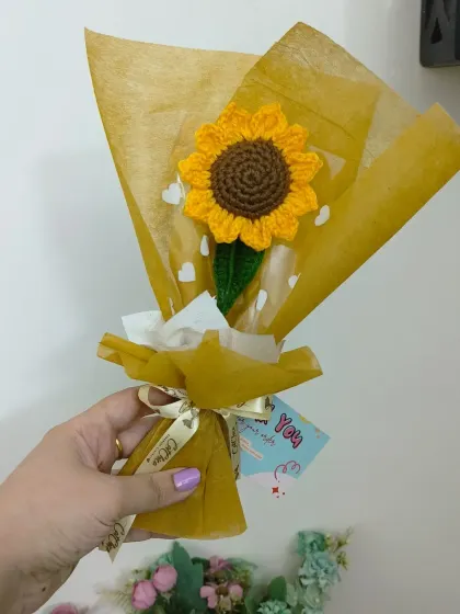 Holding one of our wrapped crochet sunflowers. Each one comes with a small card, making it a complete and thoughtful gift.