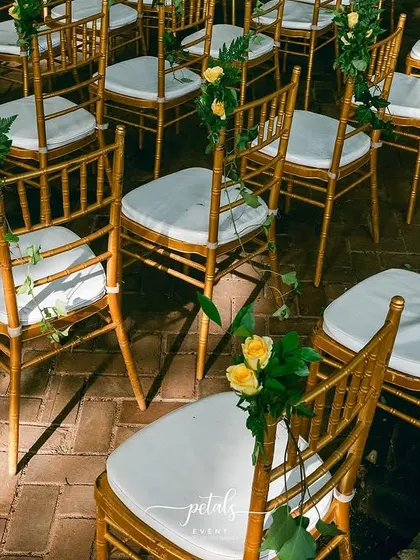 The Tiffany chairs are adorned with small bouquets of yellow roses, adding a touch of color and charm.
