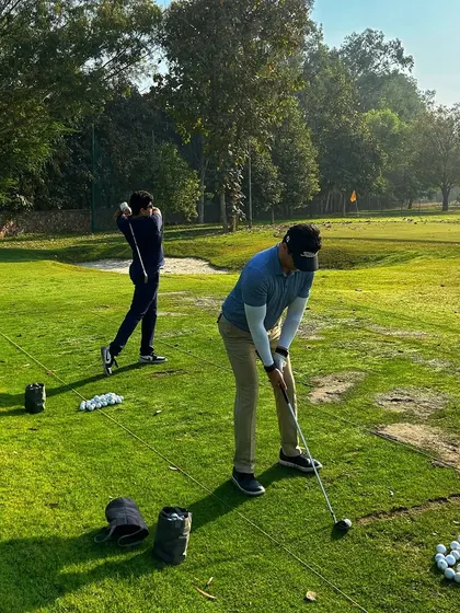 Two golfers practice their swings side-by-side, pushing each other to get better.