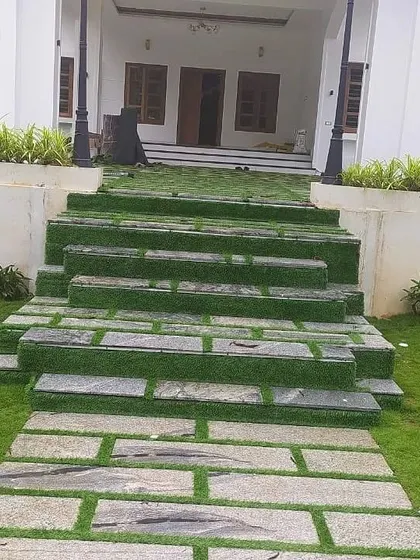 We designed these wide, welcoming steps using stone slabs and artificial grass strips. This approach integrates the staircase into the surrounding lawn, creating a natural transition from the lower garden to the home's entrance.