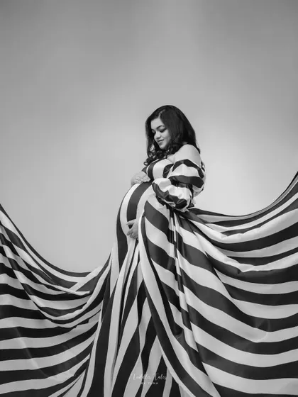 A full view of the magnificent striped gown in motion. The fabric seems to dance around the mother, creating a breathtaking visual that is both powerful and graceful.