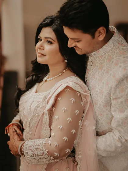A soft and romantic close-up of the couple. The groom's gentle embrace from behind and the bride's serene expression create a warm and intimate portrait.