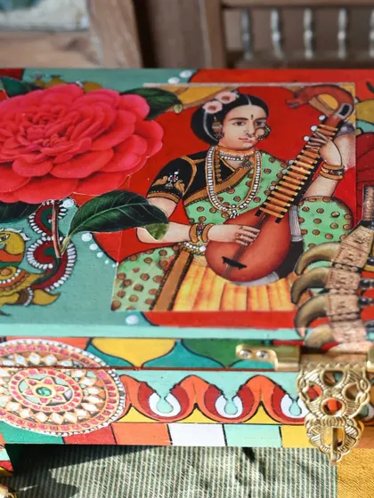 A close-up of a recently completed tabletop box, featuring a portrait of a woman playing a veena, inspired by Tanjore paintings. The rich colors and intricate details are a hallmark of this style.