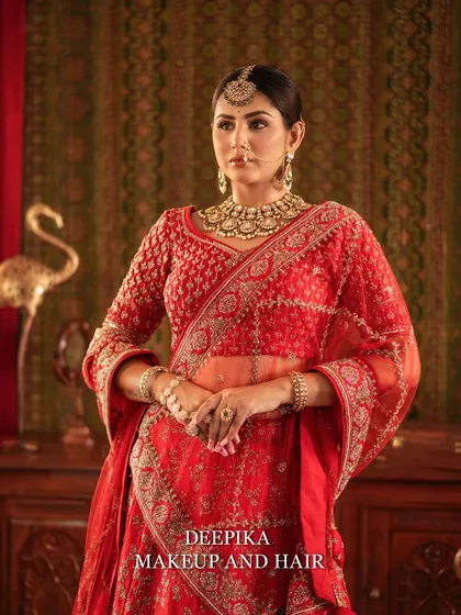 A regal portrait of a bride in a classic red lehenga. The makeup is kept timeless with defined eyes and a neutral lip, letting the outfit shine.