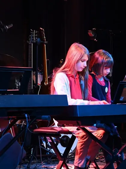 Two of our youngest students sharing a keyboard to perform a duet. We make learning and performing fun and accessible for everyone.