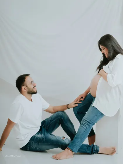 A full-length portrait from a casual studio maternity session. The relaxed pose and matching denim outfits create a modern and relatable feel.