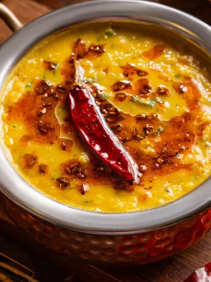 A close-up of Dal Tadka for Sadakchaap, with a sizzling red chili on top. This shot emphasizes the homestyle, comforting nature of the dish, a key selling point for delivery.