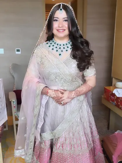 Another beautiful shot of Priyal's contemporary bridal look. The focus is on her radiant skin and the stunning emerald jewelry, which pops against the soft pastel palette.