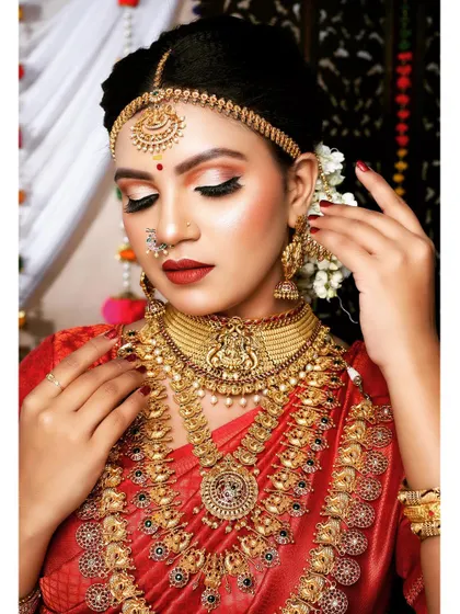 A close-up of a bride wearing a traditional matte gold choker and haram. The matha patti and nath complete this classic and elegant bridal look.