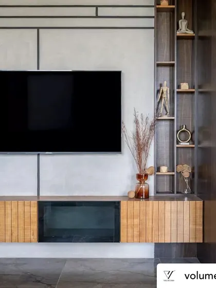 A straight-on view of the living room media wall. The geometric pattern of lines on the concrete-finish wall adds a subtle layer of detail, while the wood console and vertical shelving unit bring warmth and balance to the composition.