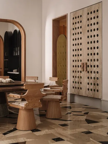 Another angle of the dining room, looking towards a secondary entrance. The perforated wooden screen and bold flooring create a space that is rich in pattern and texture.