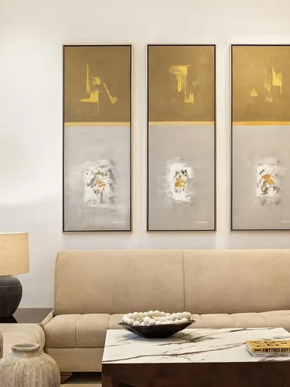 Art and texture bring warmth to the formal living area. Here, a triptych of abstract paintings complements the neutral tones of the sofa and the organic forms of the ceramic vases, creating a composition of quiet sophistication.