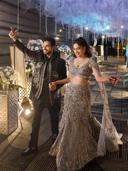 A candid moment of the happy couple making their grand entrance. Her radiant makeup ensures she is glowing from every angle, even in motion.