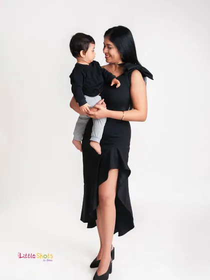 A full-length portrait showing a mother's loving embrace. The simple white background keeps the focus on the beautiful connection between her and her son.