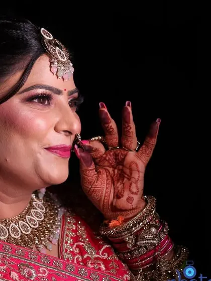 A beautiful side-profile portrait of the bride, highlighting her elegant hairstyle, makeup, and the details of her earrings against a dark background.