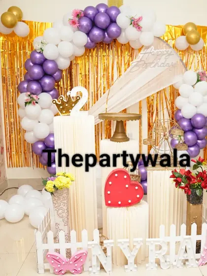 A purple, pink, and white balloon ring with a gold shimmer backdrop.