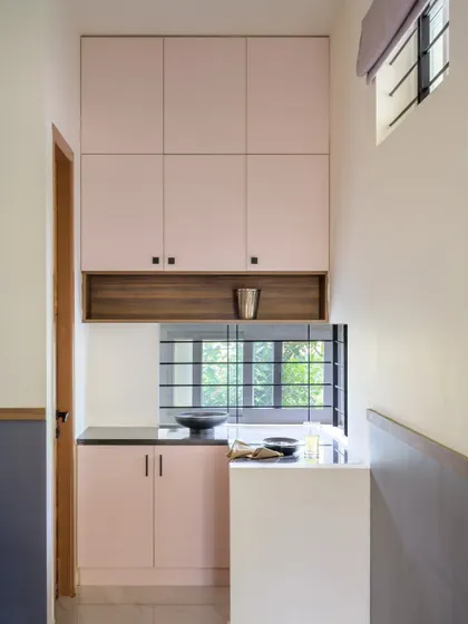This compact pantry in 'Villa Calmora' uses blush pink cabinets and a dark countertop. Even in a small, narrow space, I ensured there was ample storage and a functional work surface.
