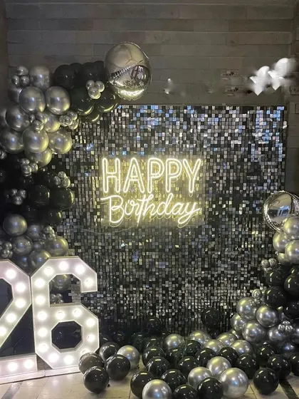 This is another example of a glamorous shimmer wall backdrop, here in a black and silver theme for a 26th milestone. The combination of chrome balloons, a neon sign, and marquee numbers creates a high-energy party atmosphere.
