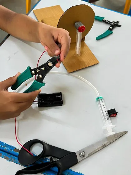 A student uses a wire stripper to prepare the wiring for the motor in the disc brake project. This is a key step in learning basic electronics and tool safety.