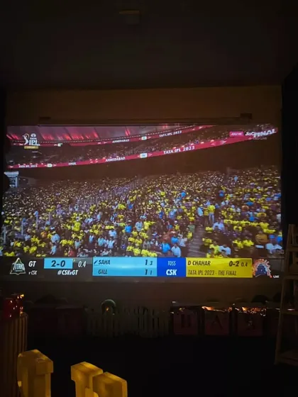 A wide shot of the stadium during an IPL match screening. You can feel the energy of the crowd, but from the comfort of our plush recliners.