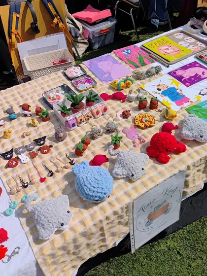 Another angle of my market stall, showing the full range of my handmade accessories. You can spot the fluffy crochet stingrays, tiny potted plants, and a wide selection of my cross-stitch pins and keychains ready for new homes.