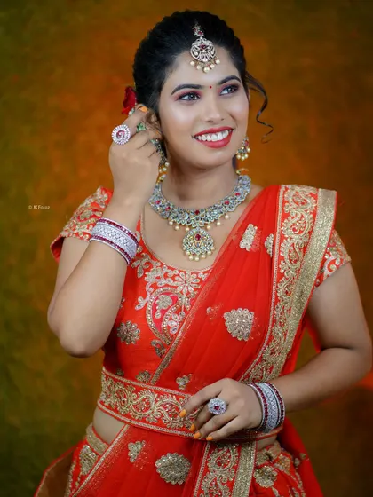 Adjusting her earrings, this model showcases the complete bridal look with our red lehenga and matching jewellery set. It's a perfect combination for a memorable reception.