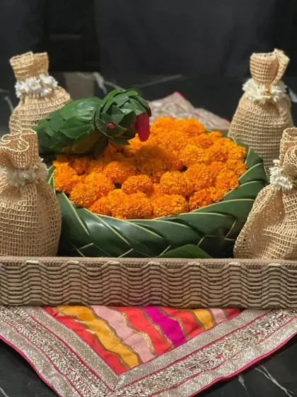 A customized festive hamper I created for a client. This gift includes a charming floral basket with a parrot made from leaves, surrounded by traditional potli bags, making for a unique and personal present.