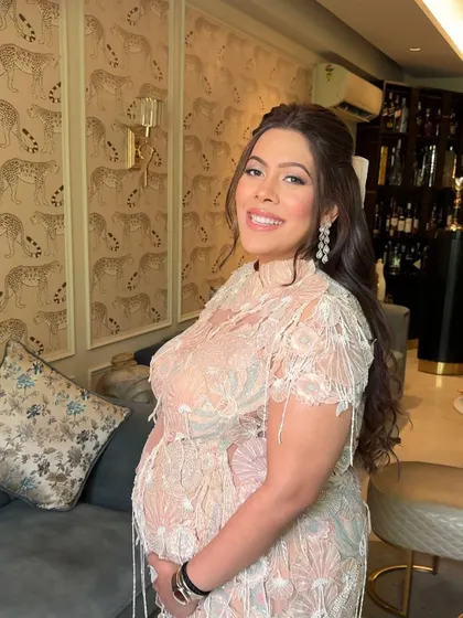 A beautiful mom-to-be at her baby shower, her hair styled in a sweet and elegant half-updo with a large bow.