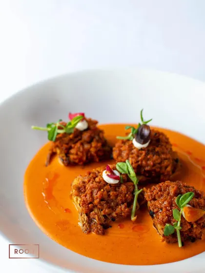 The Achari Artichoke dish, beautifully plated in a rich tomato-based gravy. It's a creative vegetarian option that is full of bold and exciting flavours.