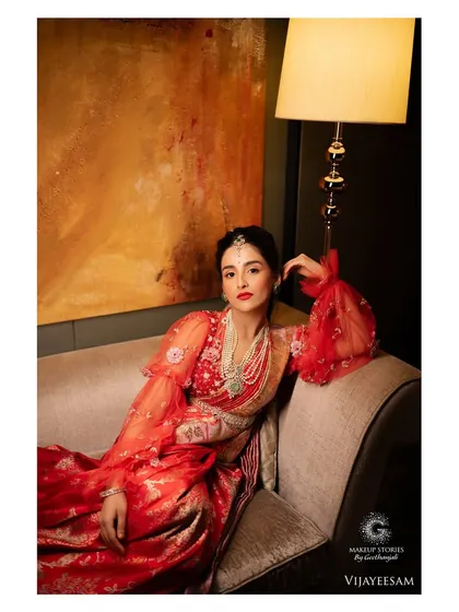 Krishna looking regal in a modern fusion saree. The makeup features a bold red lip and defined eyes, creating a look that is both traditional and contemporary, perfect for a sangeet or reception.