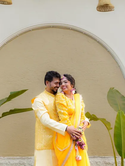 A sweet and happy portrait of a couple during their Haldi ceremony, dressed in matching yellow outfits.