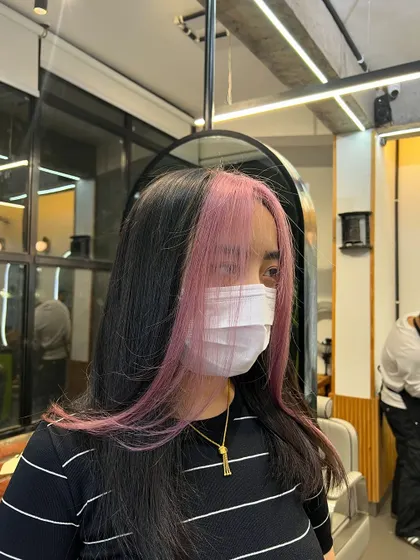 A perfect example of creative color placement. These pastel pink face-framing highlights add a fun, modern twist to a natural base color. It's a great way to express your personality and brighten your features without committing to an all-over color.