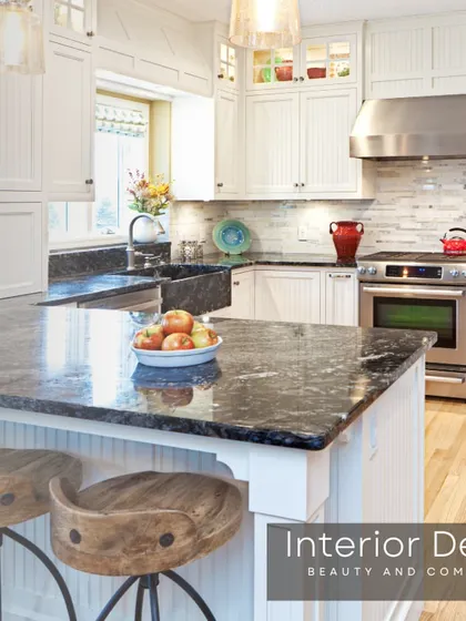 A classic American-style kitchen with white paneled cabinets and a dark granite countertop. The design includes a large island with bar stool seating, perfect for breakfast and casual meals.