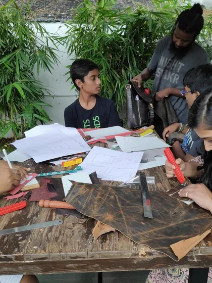 A facilitator guides participants through the basics of leather craftsmanship. In this workshop, attendees learn techniques to create their own wallets and journal covers using a simple set of tools.