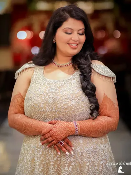 A lovely portrait of bride Harleen, her hands adorned with intricate henna, smiling softly.