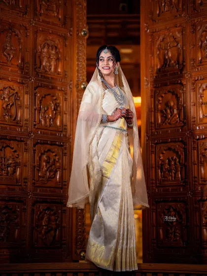 This stunning Iyer bride wanted to honor her groom's heritage by wearing a Kannadiga-style drape for one of her ceremonies. I created this elegant look for her, blending traditions beautifully against the backdrop of an intricately carved wooden doorway.