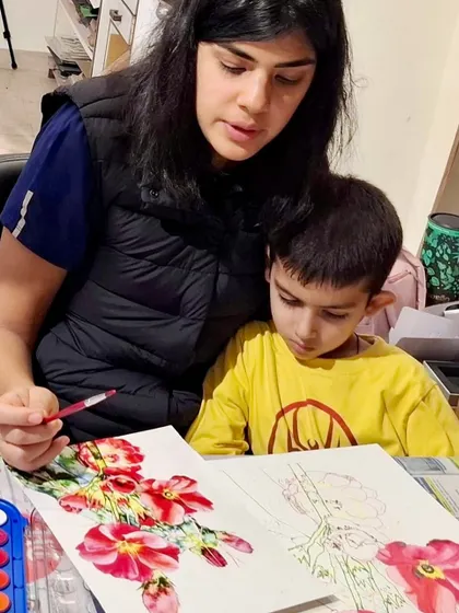 I encourage artistic development at every age. Here, an older student provides gentle guidance to a younger child as they work together on a beautiful floral watercolor painting.
