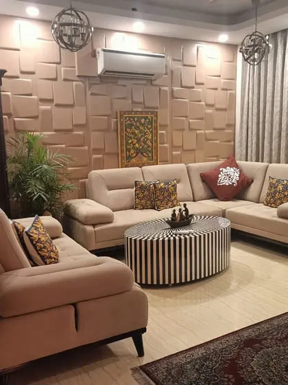 This living room is part of a Bohemian-themed home, featuring a comfortable beige sectional sofa and a unique black-and-white striped coffee table. The 3D wall panels add texture and depth.