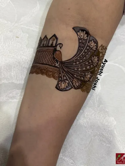 A stunning peacock with a long, flowing tail, designed as a statement piece on the upper arm.