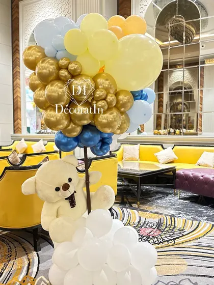 A large teddy bear and balloon sculpture adds a grand and playful element to the event space.