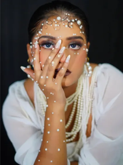 A high-fashion editorial look, with the model's face partially obscured to draw attention to the pearl details.