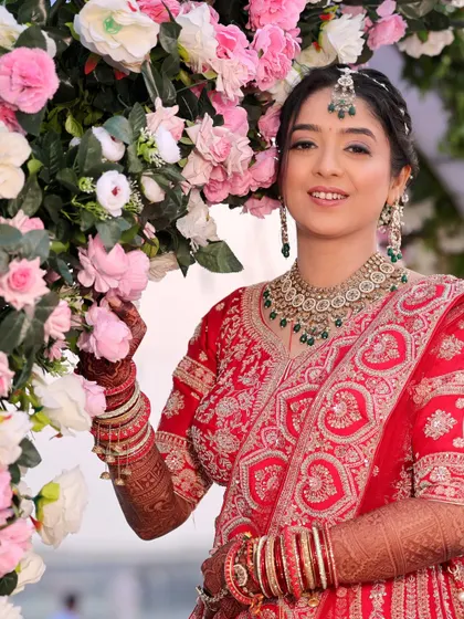 A lovely portrait of the bride standing by a floral arch. Her bright smile and the beautiful decor create a fresh and vibrant image from the wedding day.