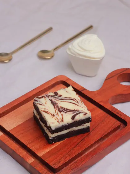 A single Cheesecake Brownie stacked, showing the distinct layers of rich brownie and creamy cheesecake. It's a dessert that's both elegant and satisfying.