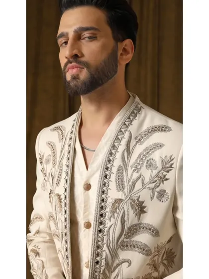 A detailed view of the 'Pragyan' shrug's embroidery. This shot highlights the cream and gold threadwork, showcasing the garden-inspired motifs and the precision of the hand-stitching.