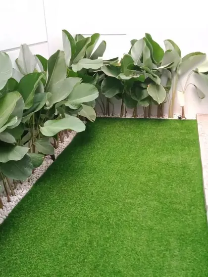 A clean and simple landscape design for a narrow space. We used artificial turf for the ground cover and lined the wall with large-leafed plants in a bed of white pebbles for a modern, minimalist look.
